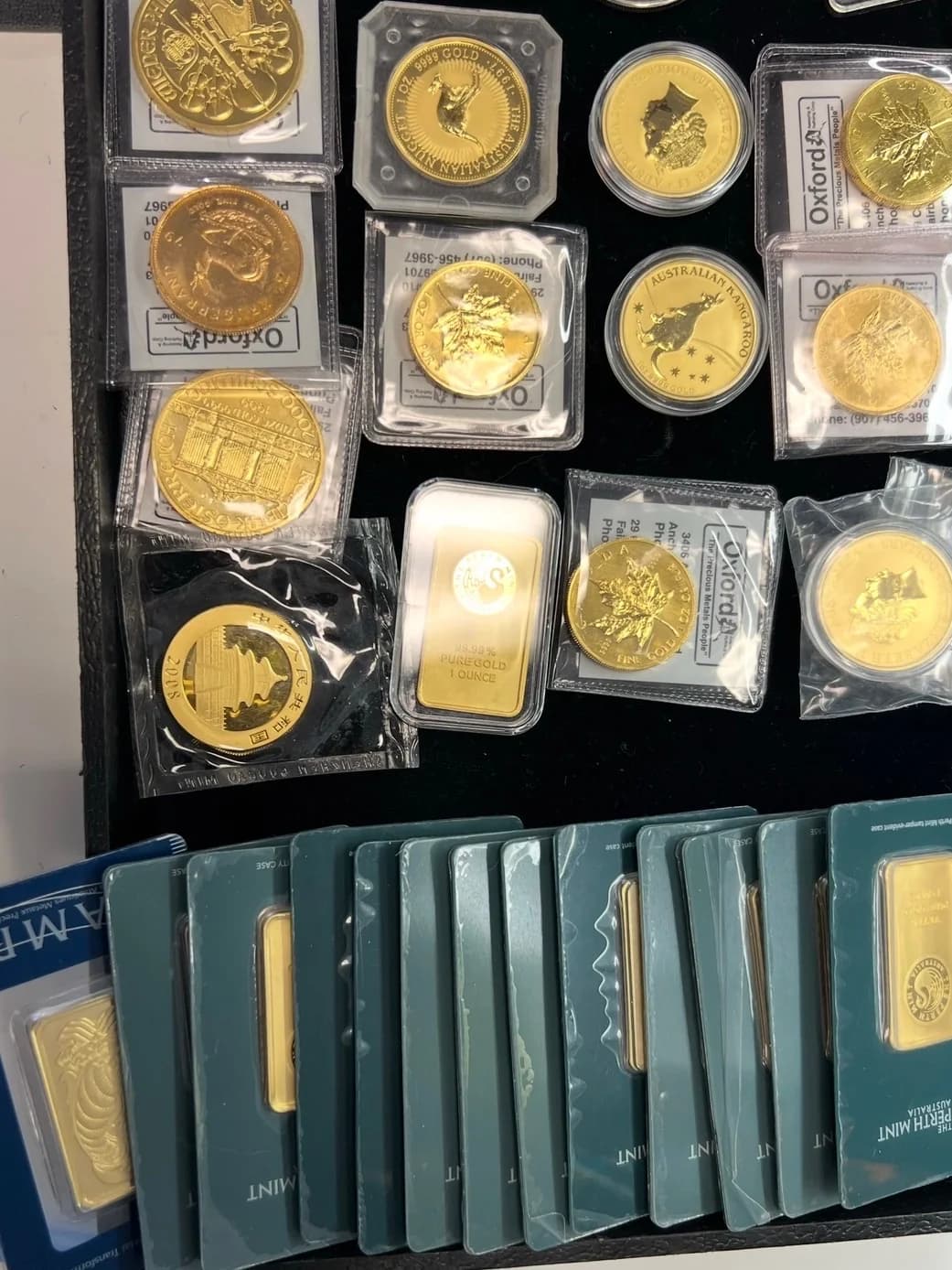 Gold coins and sealed bullion bars laid out in a display tray at The Gold Rush Store
