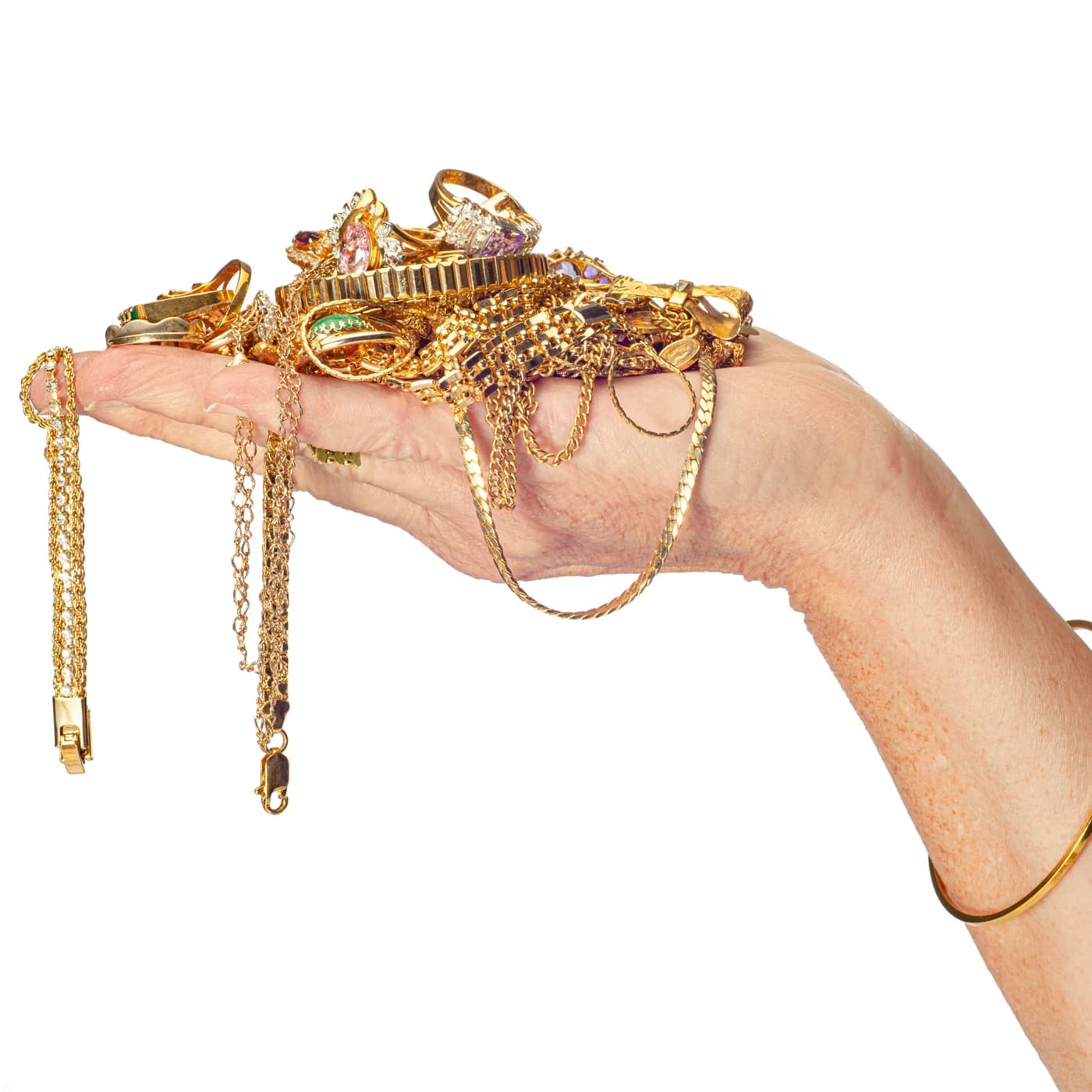An open hand holding a pile of gold chains, rings, and bracelets